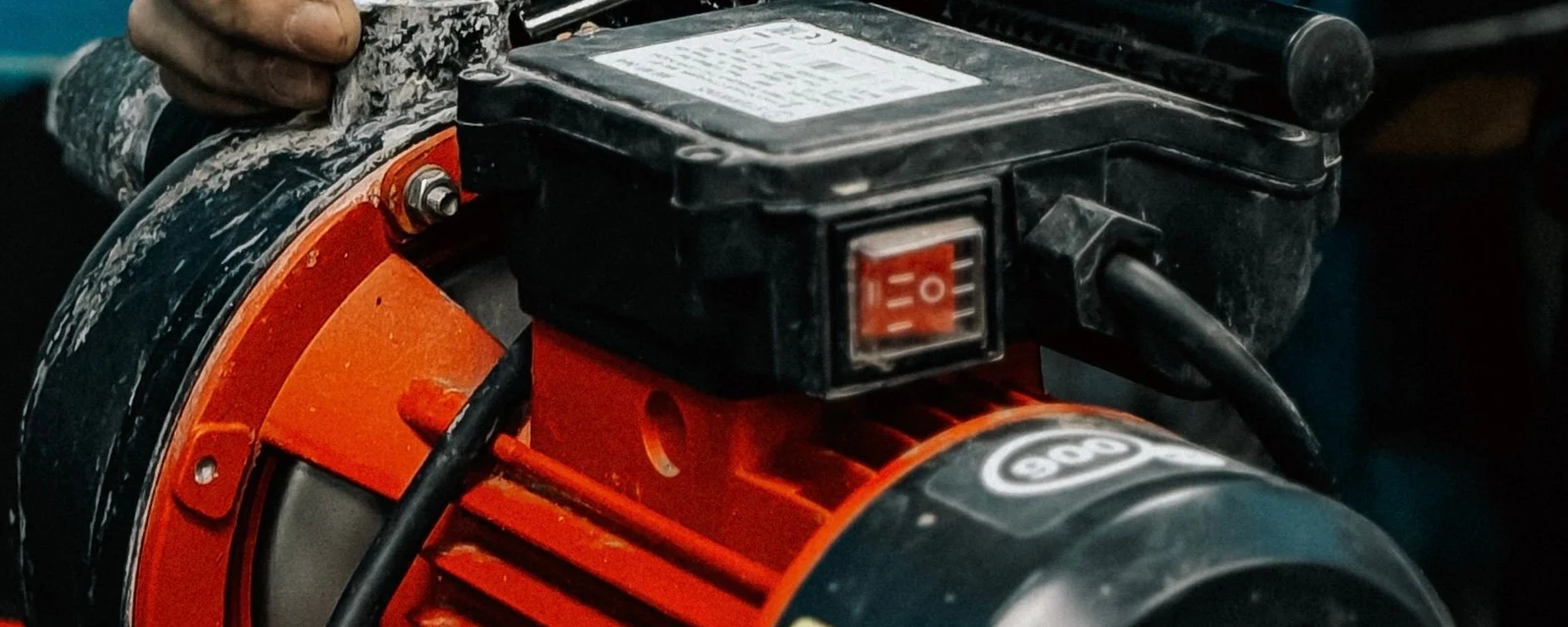 Close up of a red electric pump motor with a hand resting on it